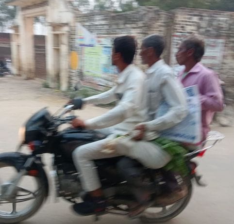 तीन सवारी बिना हेलमेट जाते स्कूटी सवार युवा। संवाद तीन सवारी बिना हेलमेट जाते स्कूटी सवार युवा। संवाद