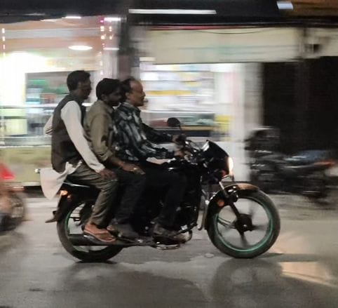 तीन सवारी बिना हेलमेट जाते स्कूटी सवार युवा। संवाद तीन सवारी बिना हेलमेट जाते स्कूटी सवार युवा। संवाद