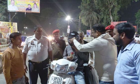 हेलमेट पहने बाइक सवार को फूल देते यातायात कर्मी व समाजसेवी। संवाद