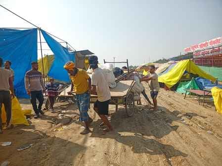 ददरी मेला में विद्युत आपूर्ति के लिए लकड़ी के खंभा को ट्रैक्टर से खींचकर ले जाते मजदूर।संवाद