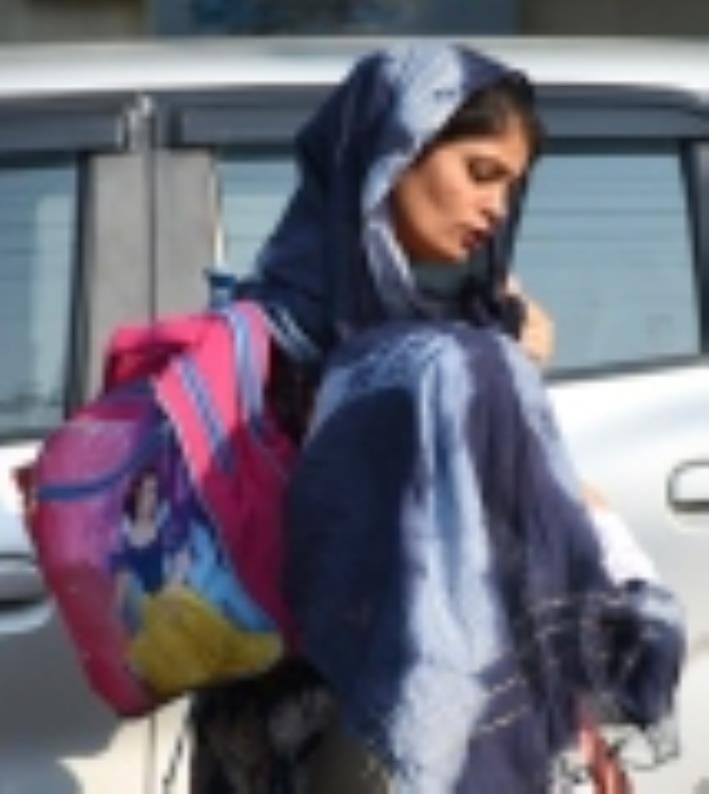गुनगुनी धूप में जाती महिला।