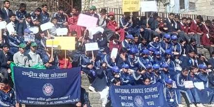 चौपाल में नशे के खिलाफ रेली में पोस्टर लेकर लोगों को जागरूक करते स्कूल की छात्रांए