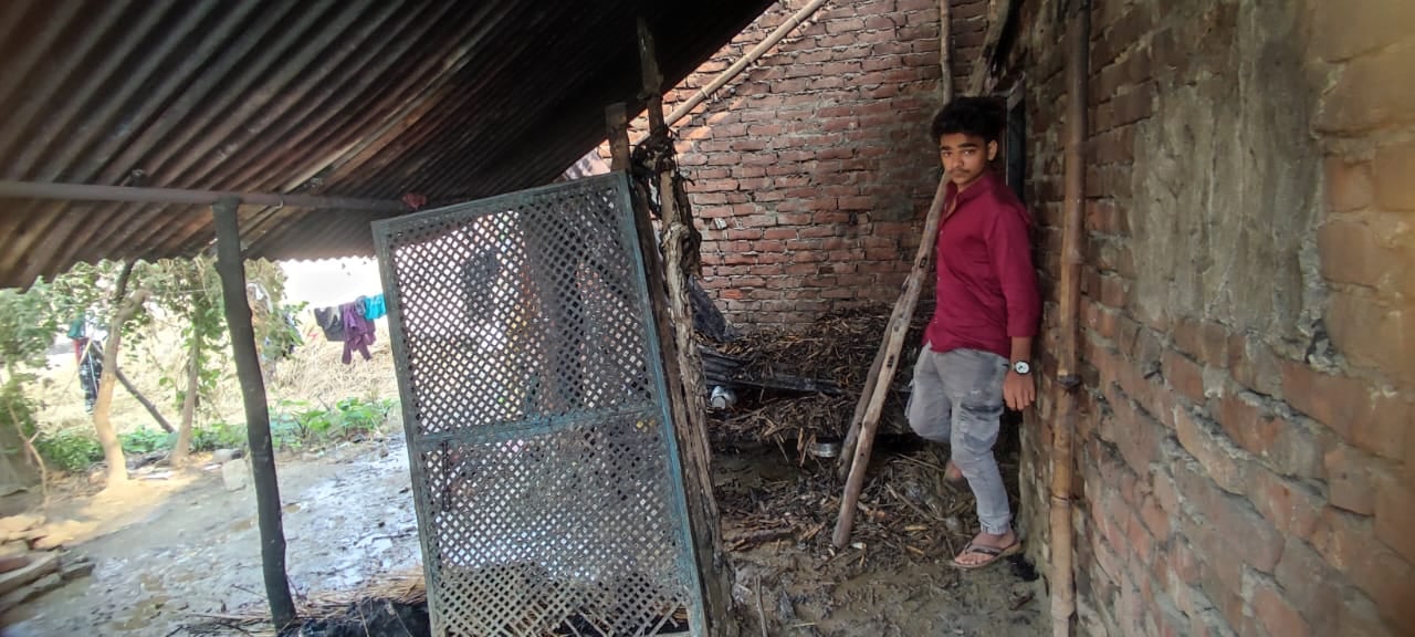 धोबहा गांव में आग लगने से जले घर के सामने खंड़े परिवार के लोग । स्राोत - ग्रामीण