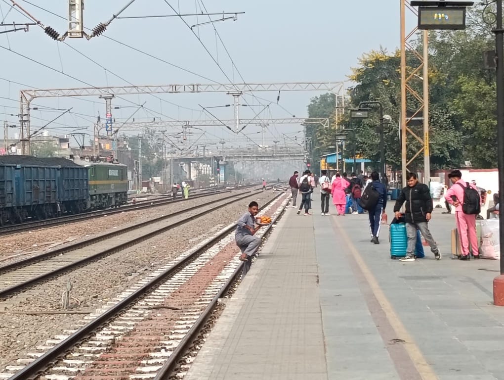 स्टेशन पर रेलवे ट्रैक पार करते यात्री। संवाद स्टेशन पर रेलवे ट्रैक पार करते यात्री। संवाद