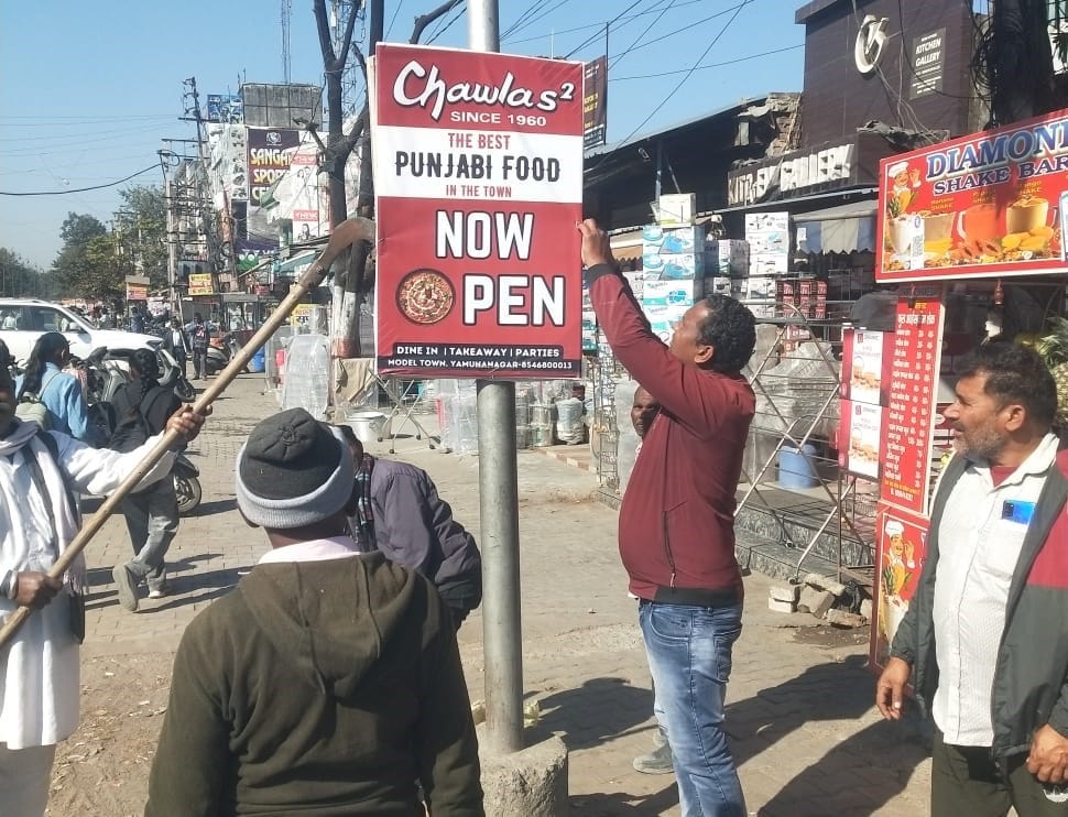 मॉडल टाउन से अवैध होर्डिंग हटाती निगम की टीम। प्रवक्ता
