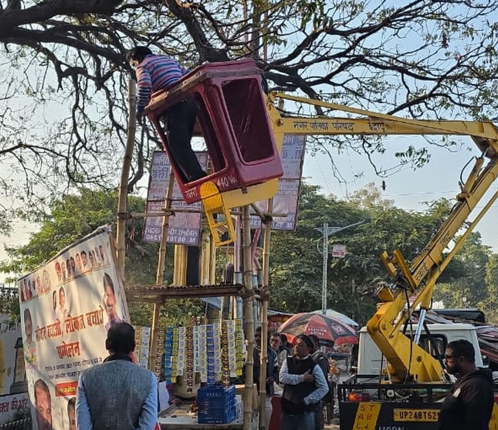 दातागंज तिराहे पर बिजली के खंभें पर लगे फ्लैक्स हटाते कर्मचारी। स्रोत पालिका