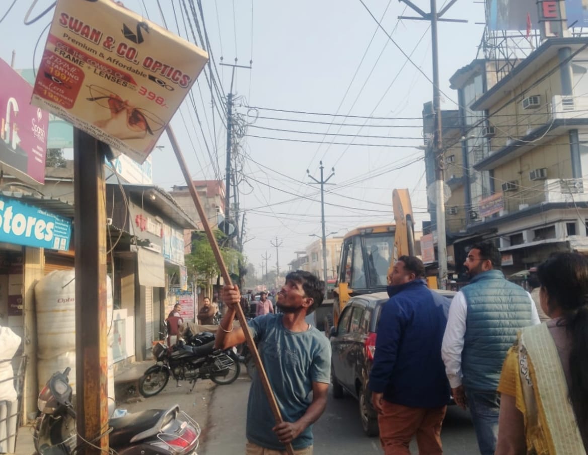 शहर में होर्डिंग्स उतरवाते नगर पालिका के अधिकारी। संवाद