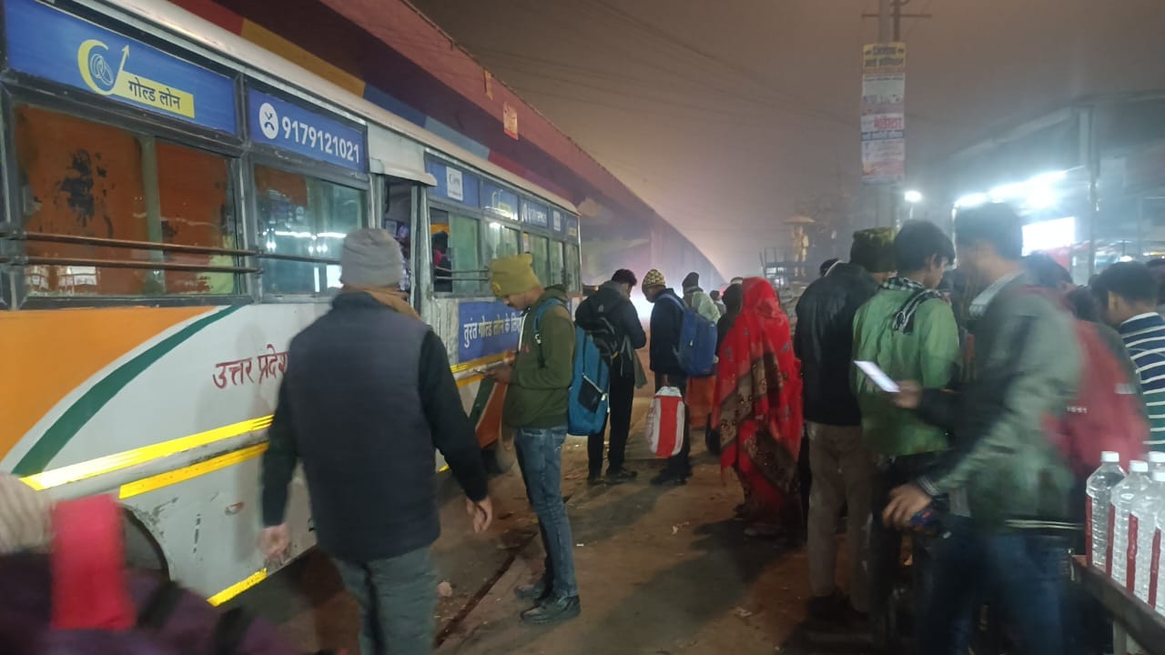 बस स्टैंड पर बसों का इंतजार करते हुए लोग । संवाद