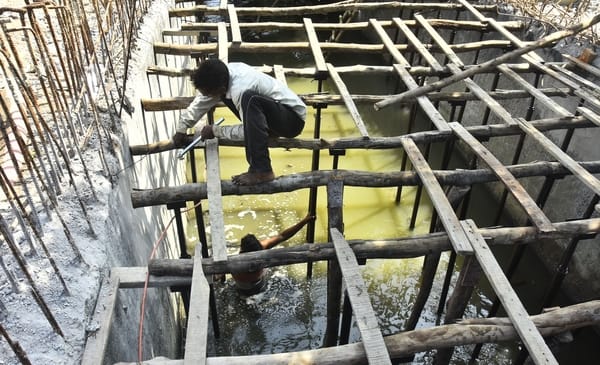 बिना सुरक्षा उपकरणों के नालों की स्लैब डालने का काम करते मजदूर।