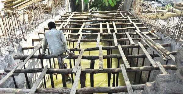 बिना सुरक्षा उपकरणों के नालों की स्लैब डालने का काम करते मजदूर।