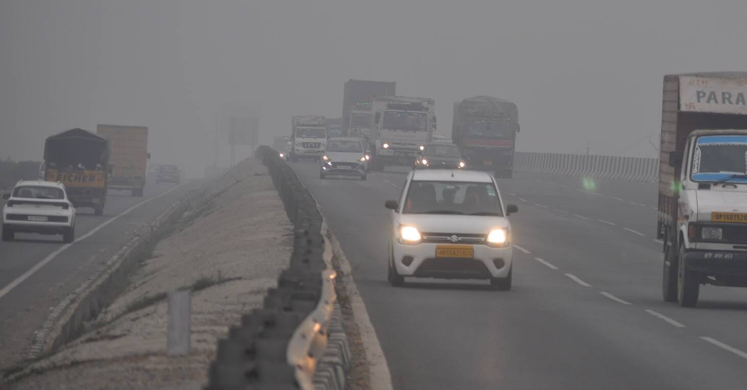 सुबह के समय तहसील चौराहे पर कोहरे में वाहनों की लाइट जलाकर सड़क पर जाते वाहन चालक। संवाद