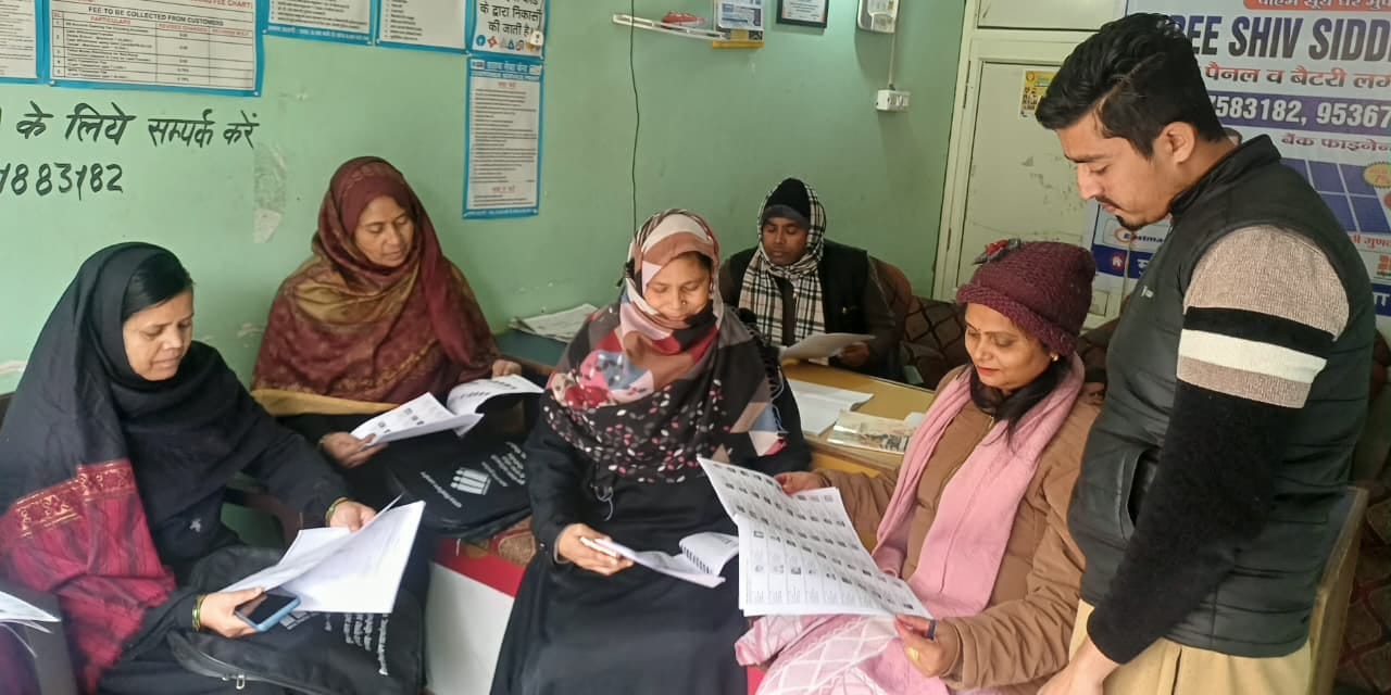 पूरनपुर नगर के एक मतदान केंद्र पर मतदाता सूची देखते लोग-संवाद पूरनपुर नगर के एक मतदान केंद्र पर मतदाता सूची देखते लोग-संवाद