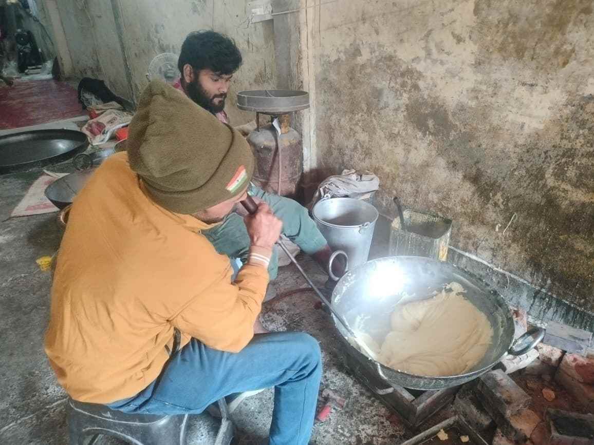 24. बड़ा बाजार में कारीगर देसी घी और चीनी को कढ़ाही में पकाकर रेवड़ी-गजक तैयार करते हुए। संवाद