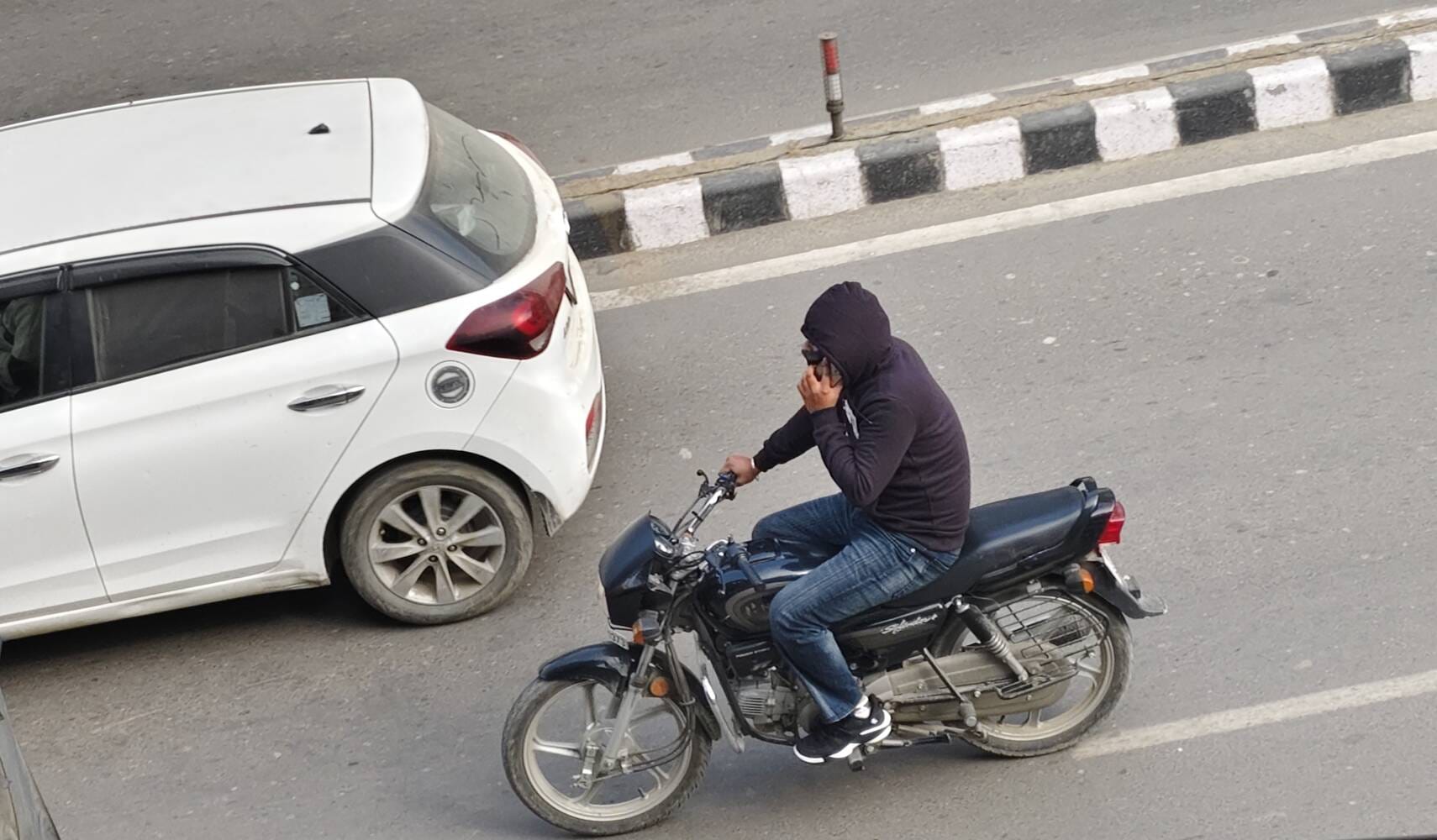 करनाल रोड पर हाथ में हेलमेट लेकर गुजरता बाइक सवार। संवाद