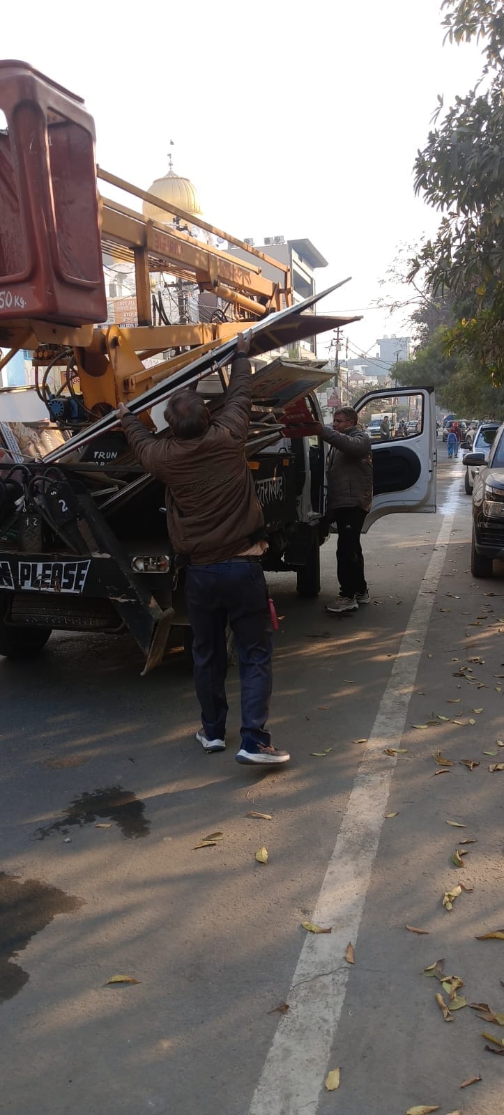 विज्ञापन बोर्ड को उतारती नगर निगम की टीम - स्वयं