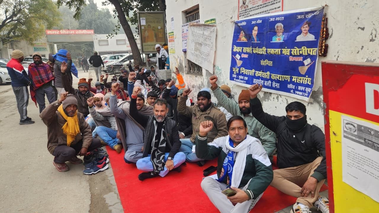 फोटो 01: सोनीपत नगर निगम कार्यालय के गेट पर ताला जड़ने के बाद संविदा सफाई कर्मियों को समझाने पह
