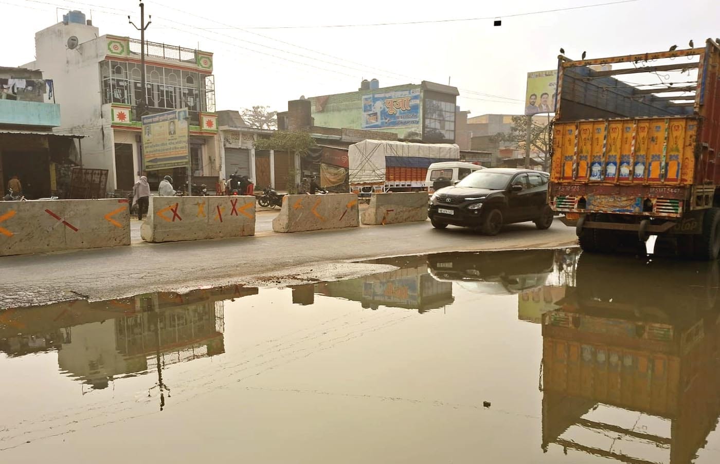 उझानी में हाईवे पर भरे नाले के पानी से होकर निकलते वाहन। संवाद
