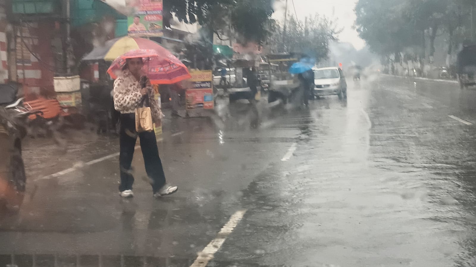 मटका चौक पर बारिश से बचने के लिए बरसाती पहनकर गुजरते वाहन चालक। संवाद