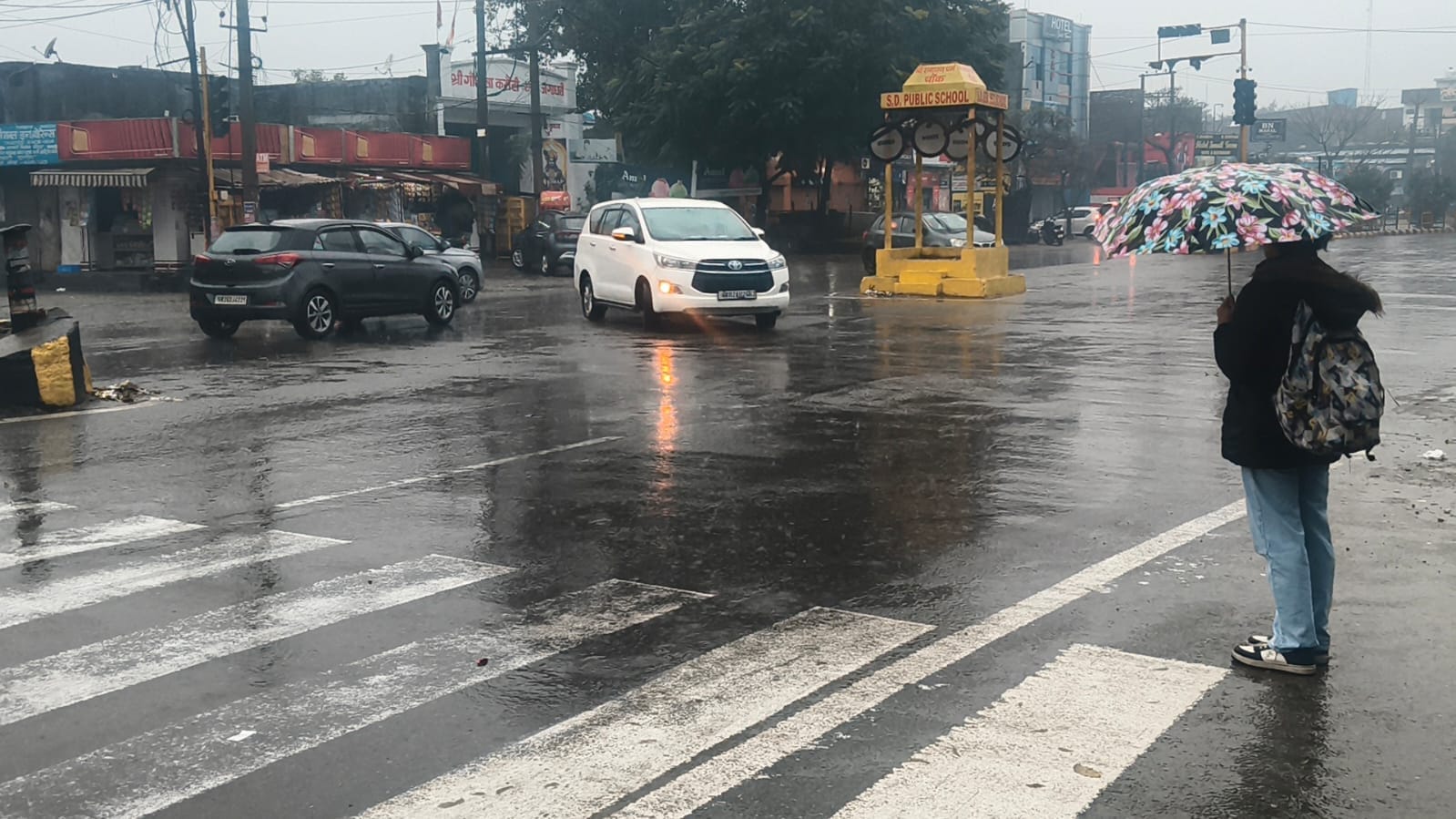 मटका चौक पर बारिश से बचने के लिए बरसाती पहनकर गुजरते वाहन चालक। संवाद