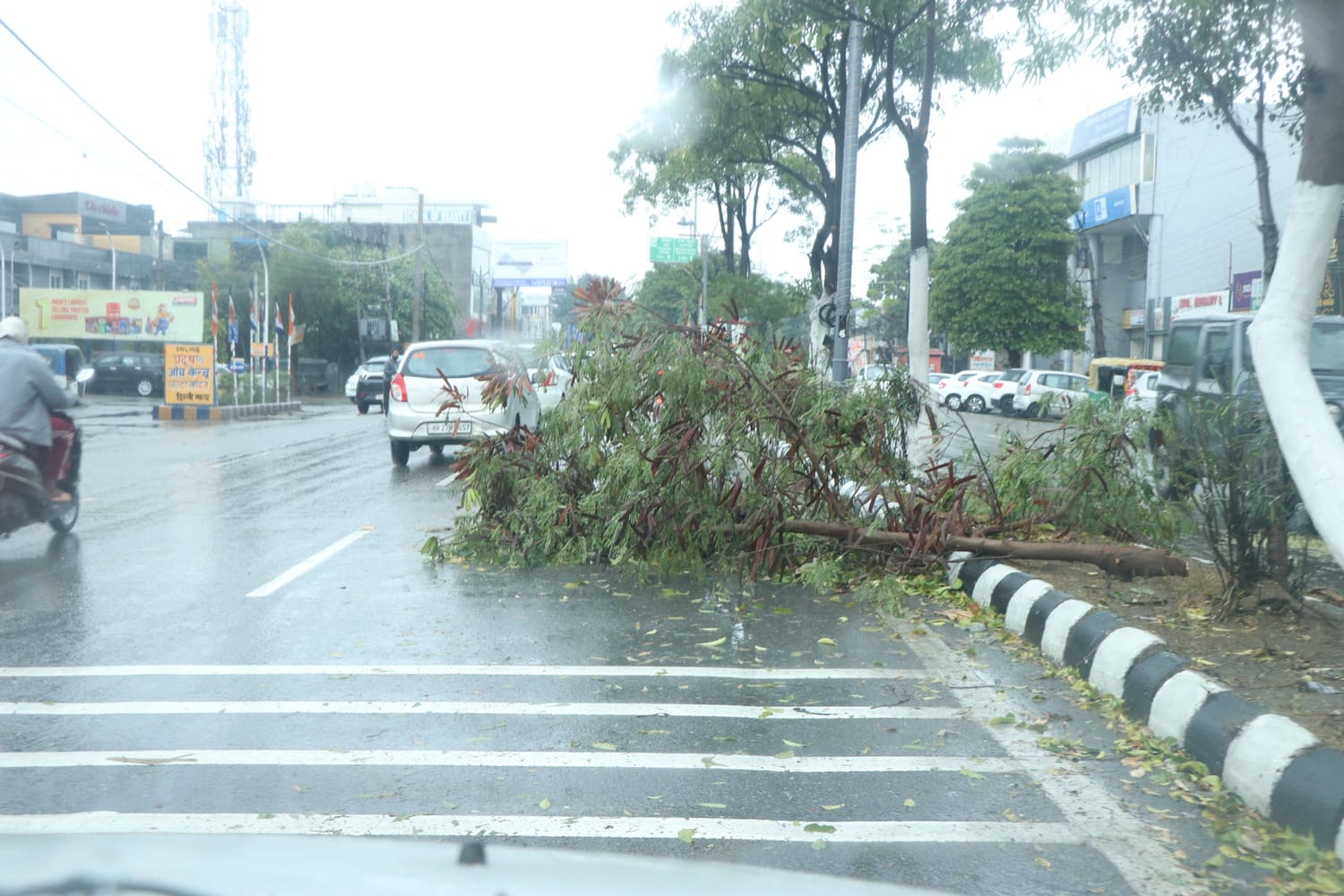 मटका चौक पर बारिश से बचने के लिए बरसाती पहनकर गुजरते वाहन चालक। संवाद
