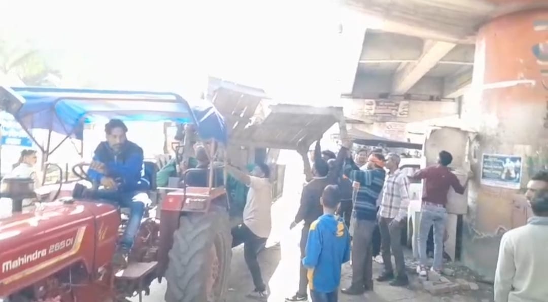 रेल ओवर ब्रिज के नीचे अतिक्रमणकारियों का सामान जब्त करते कर्मचारी ( संवाद )