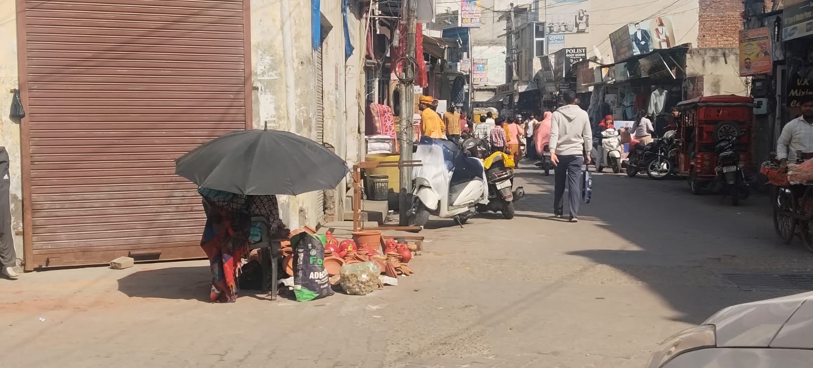कुरुक्षेत्र। दोपहर में तेज धूप होने पर छाता लेकर मिट्टी के बर्तन बेचती महिला। संवाद