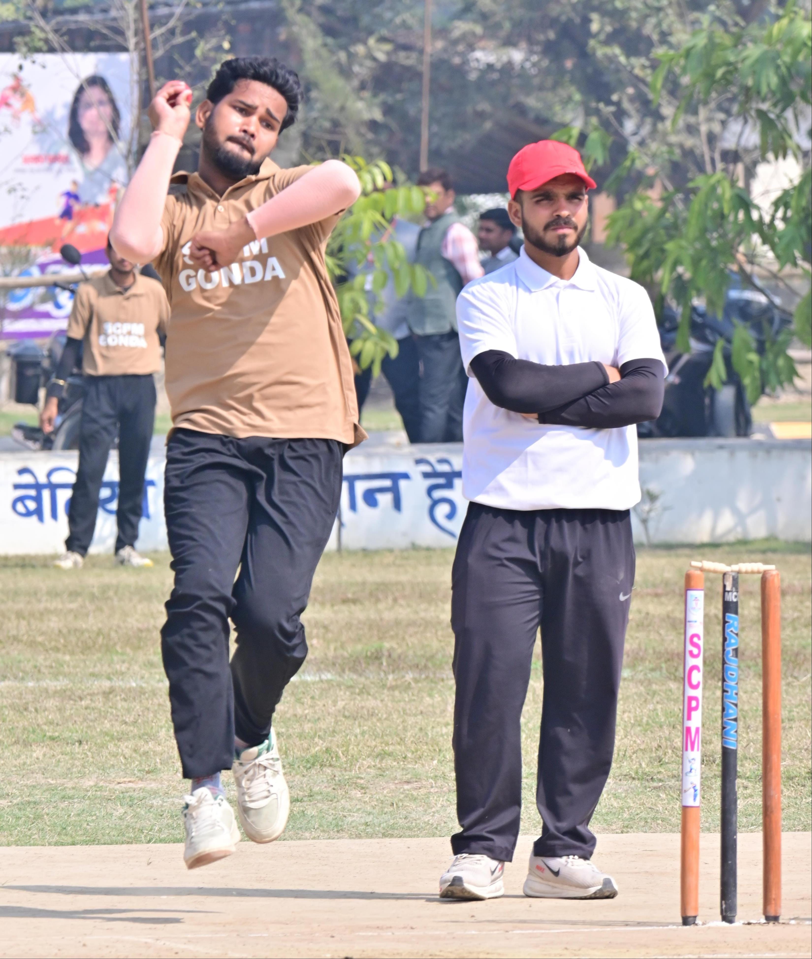 एससीपीएम खेल मैदान में आयोजित क्रिकेट प्रतियोगिता में गेंदबाजी करता खिलाड़ी और ट्रॉफी के साथ व