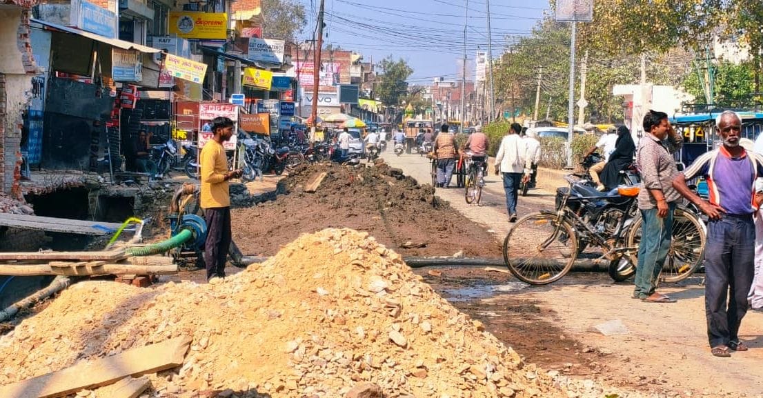 कोतवाली के सामने बह रहे नाले के पानी का पाइप हटाता मजदूर।  संवाद