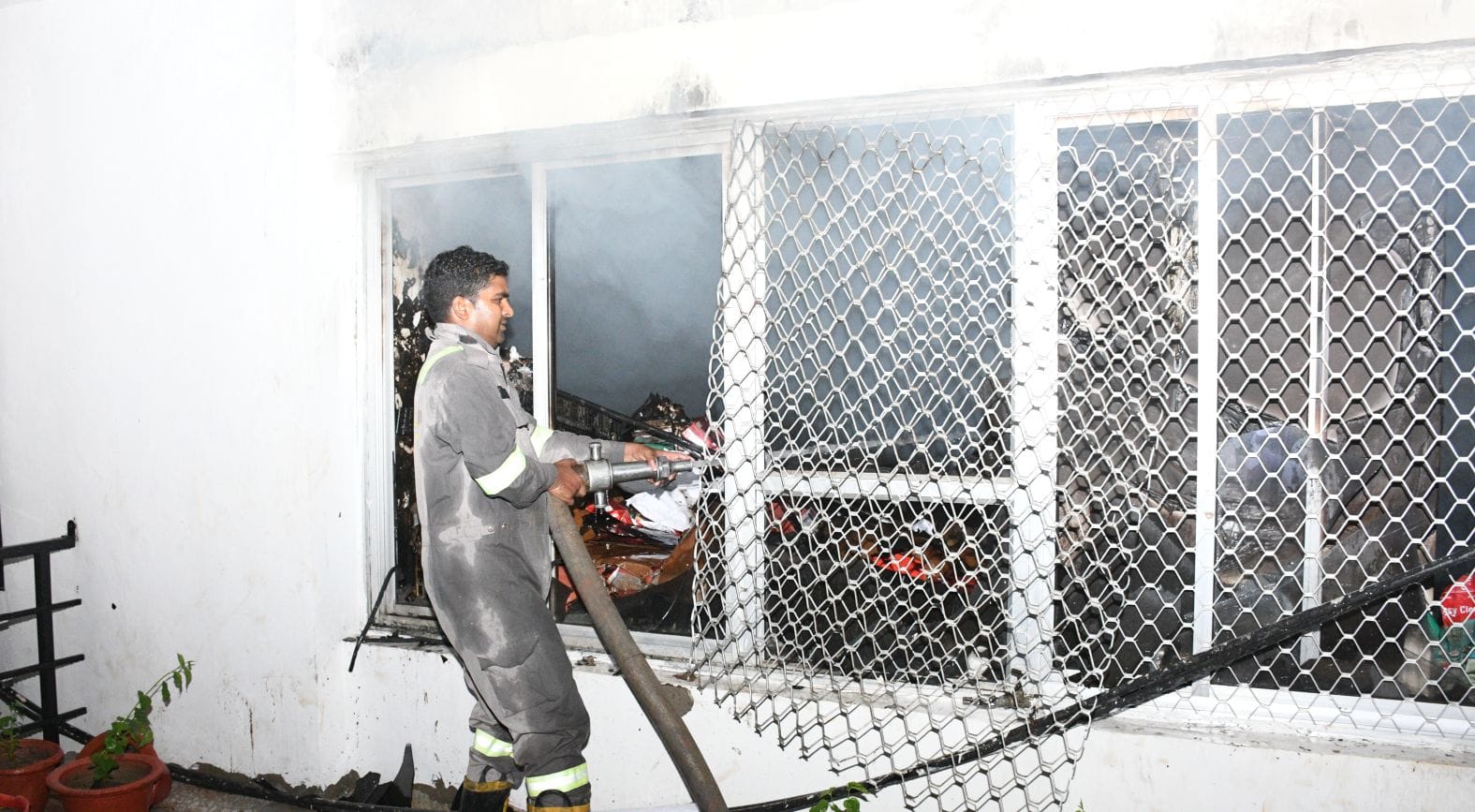 विश्वासखंड स्थित आईजी स्टांप के दफ्तर से निकलतीं लपटें और खिड़की तोड़कर आग बुझाते दमकल कर्मी।