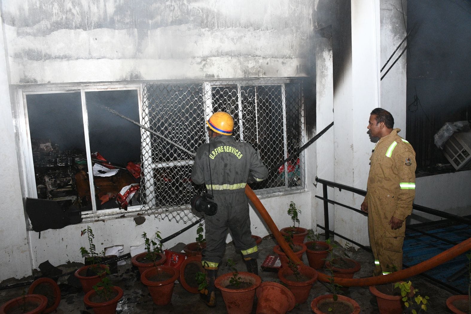 विश्वासखंड स्थित आईजी स्टांप के दफ्तर से निकलतीं लपटें और खिड़की तोड़कर आग बुझाते दमकल कर्मी।