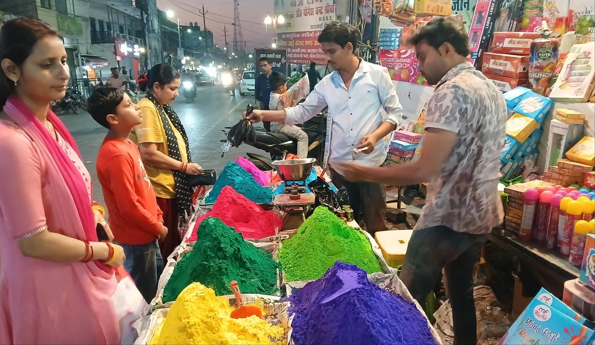शहर में रविवार को होली के लिए रंग, पिचकारी व नमकीन खरीदते लोग। संवाद शहर में रविवार को होली के लिए रंग, पिचकारी व नमकीन खरीदते लोग। संवाद
