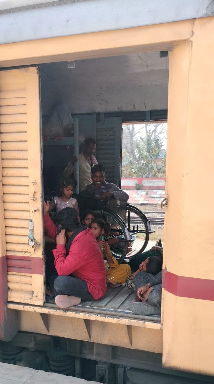 रेलवे स्टेशन पर प्लेटफॉर्म नंबर एक पर जमीन पर  बैठकर ट्रेनों का इंतजार करते यात्री। संवाद