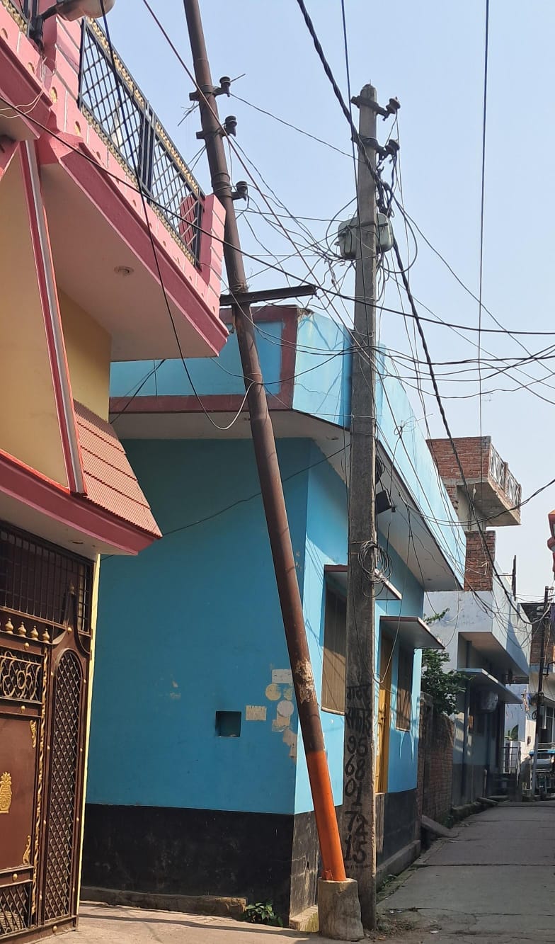 शहर के दूधिया मंदिर मार्ग लगा झुका खंभा व गली में झूलता तार। संवाद