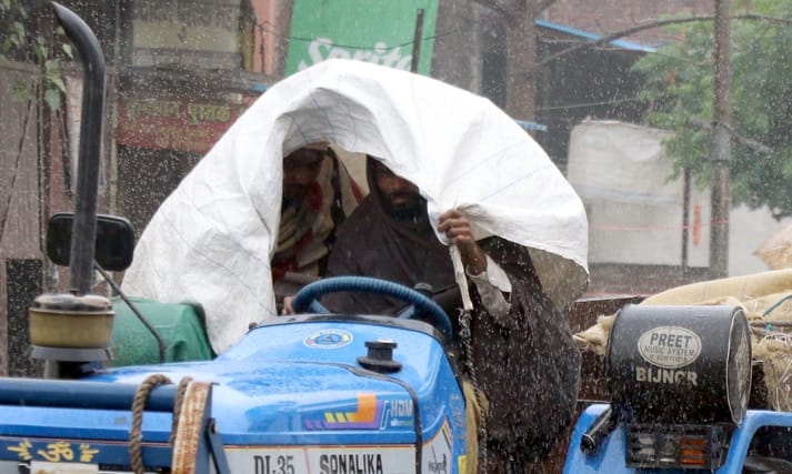 बिजनौर में शुक्रवार को हुई बारिश में बच्चों को छाता लगाकर ले जाती महिलाएं। संवाद