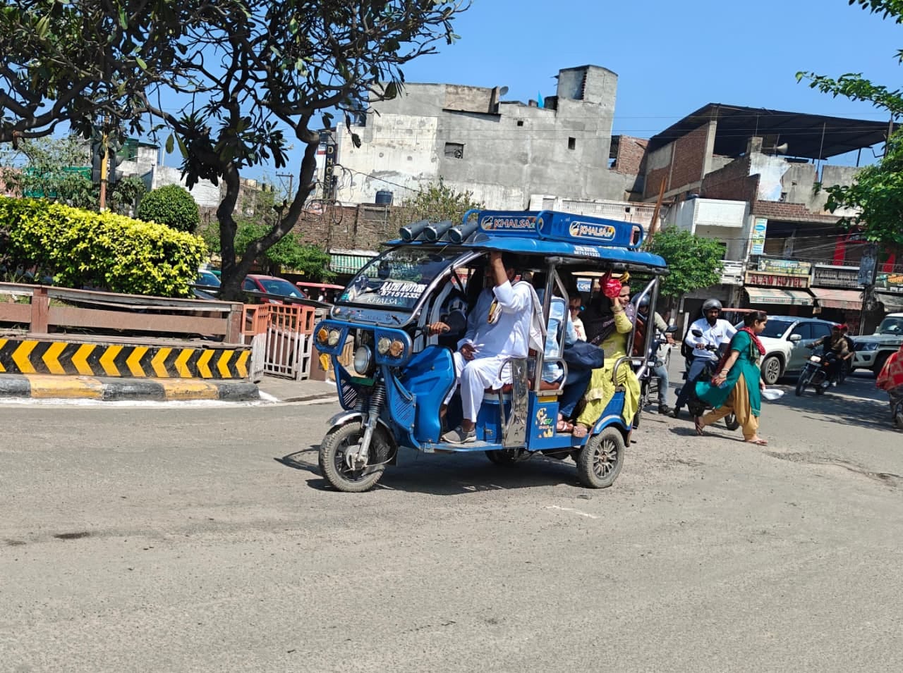 सड़क पर खड़ा अधिक चौड़ाई क्षमता वाला ई-रिक्शा। संवाद