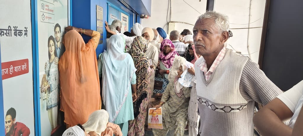 बैंक शाखा की सीढ़ियों पर बैठकर इंतजार करते बुजुर्ग। संवाद बैंक शाखा की सीढ़ियों पर बैठकर इंतजार करते बुजुर्ग। संवाद