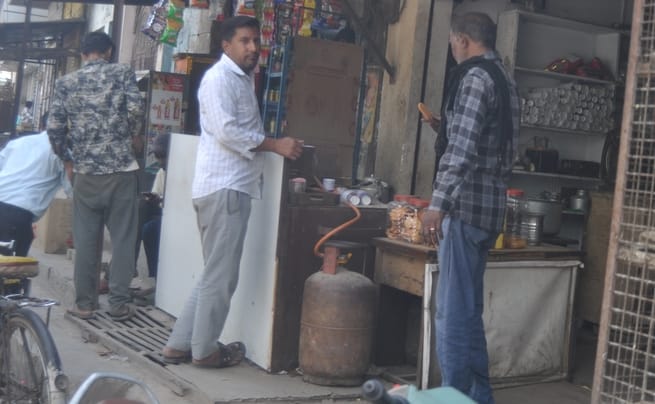 अपना घर कालोनी में गैस सिलिंडर लेने के लिए धूप में सिलिंडर पर बैठी महिला। संवाद अपना घर कालोनी में गैस सिलिंडर लेने के लिए धूप में सिलिंडर पर बैठी महिला। संवाद