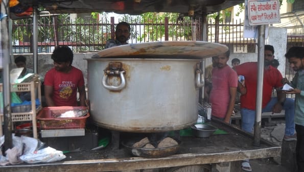 अपना घर कालोनी में गैस सिलिंडर लेने के लिए धूप में सिलिंडर पर बैठी महिला। संवाद अपना घर कालोनी में गैस सिलिंडर लेने के लिए धूप में सिलिंडर पर बैठी महिला। संवाद