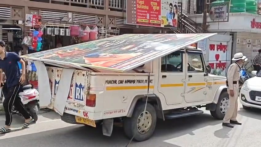 नगर निगम हमीरपुर के तहत अवैध होर्डिंग्स को हटाते हुए कर्मचारी। संवाद