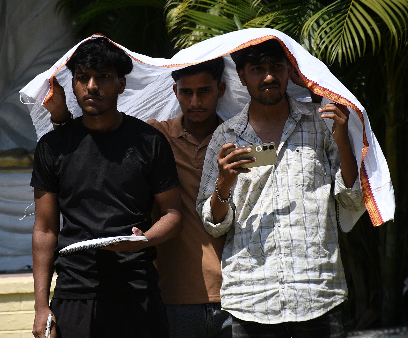 सुबह में हुई बारिश और दोपहर में धूप से बचते युवक। 