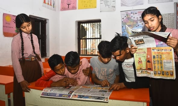 स्कूलों में अखबार पढ़ते बच्चे। स्कूलों में अखबार पढ़ते बच्चे।