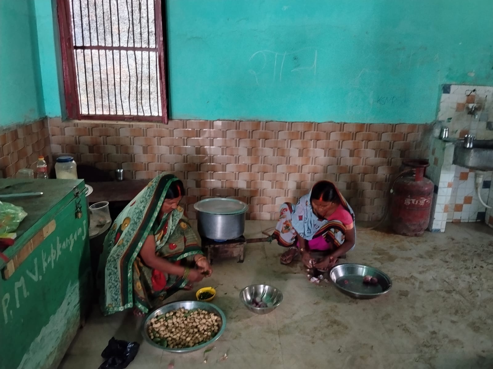 फाजिलनगर क्षेत्र के विद्यालय में चूल्हे पर लकड़ी से खाना पकातीं रसोईया।संवाद