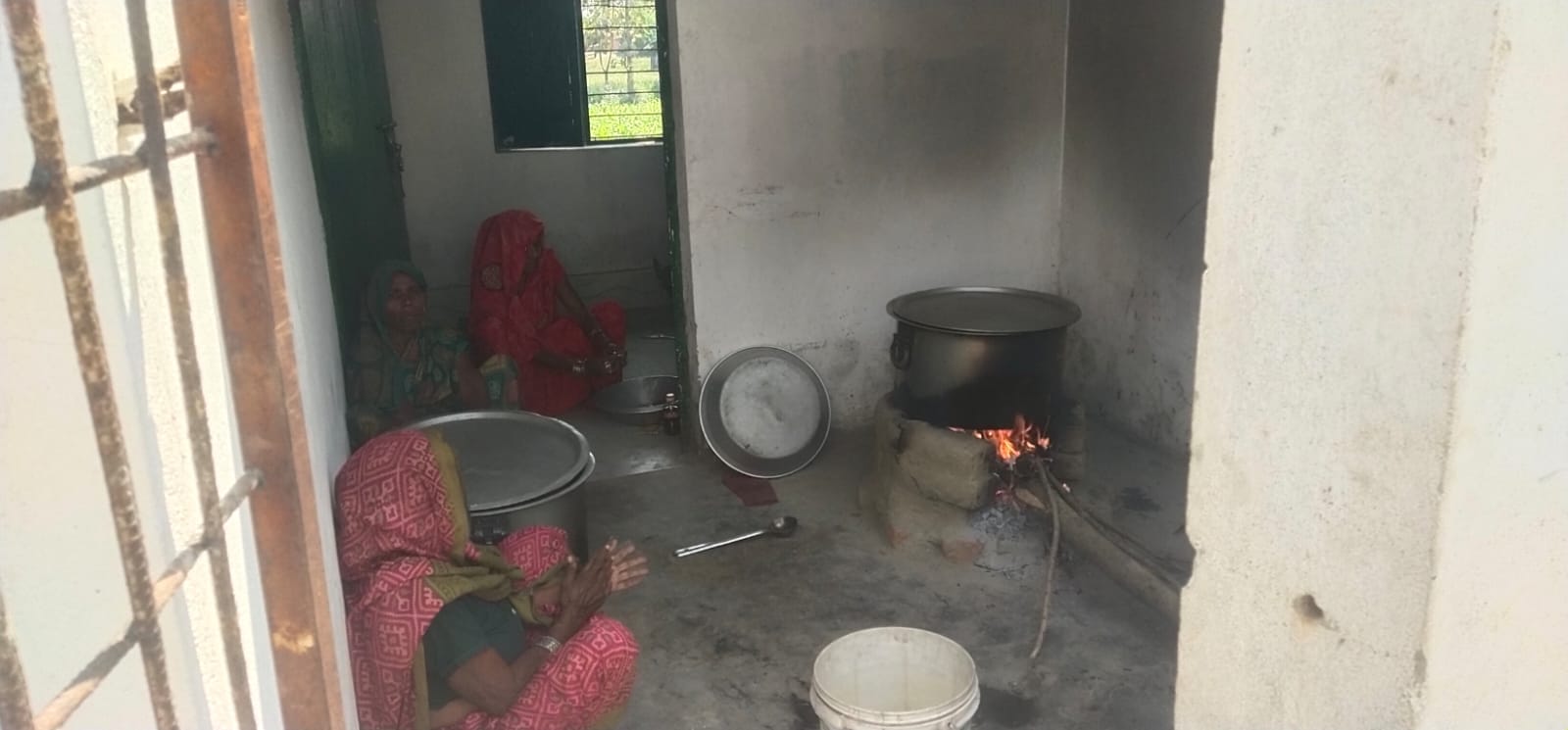 फाजिलनगर क्षेत्र के विद्यालय में चूल्हे पर लकड़ी से खाना पकातीं रसोईया।संवाद