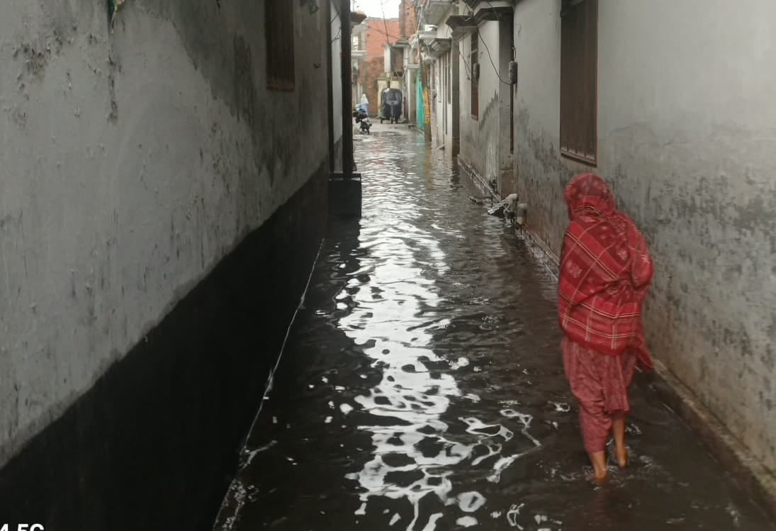 स्टेशन मार्ग पर भरे तालाब जैसे पानी से गुजरते राहगीर। संवाद