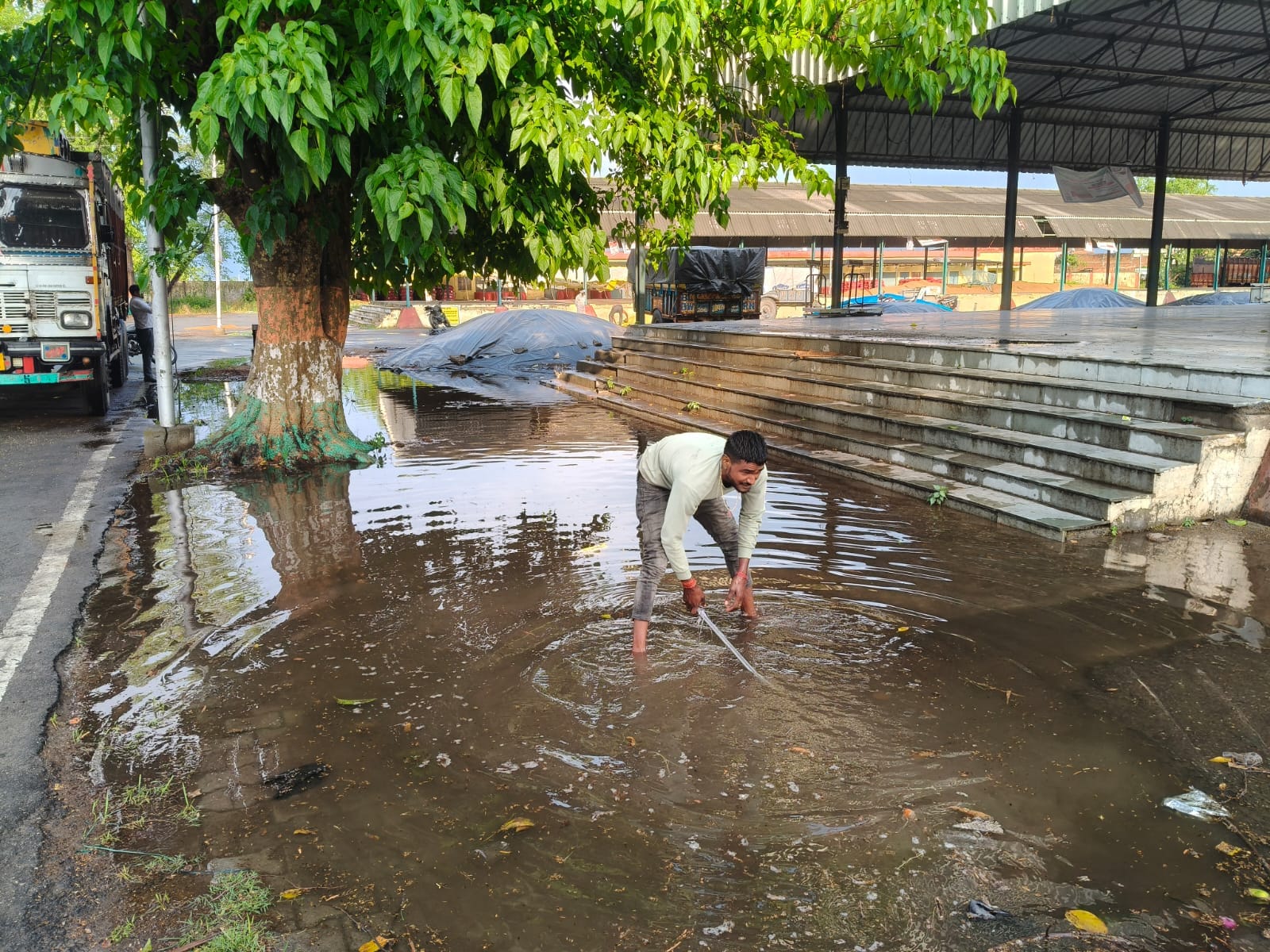 स्टेशन मार्ग पर भरे तालाब जैसे पानी से गुजरते राहगीर। संवाद