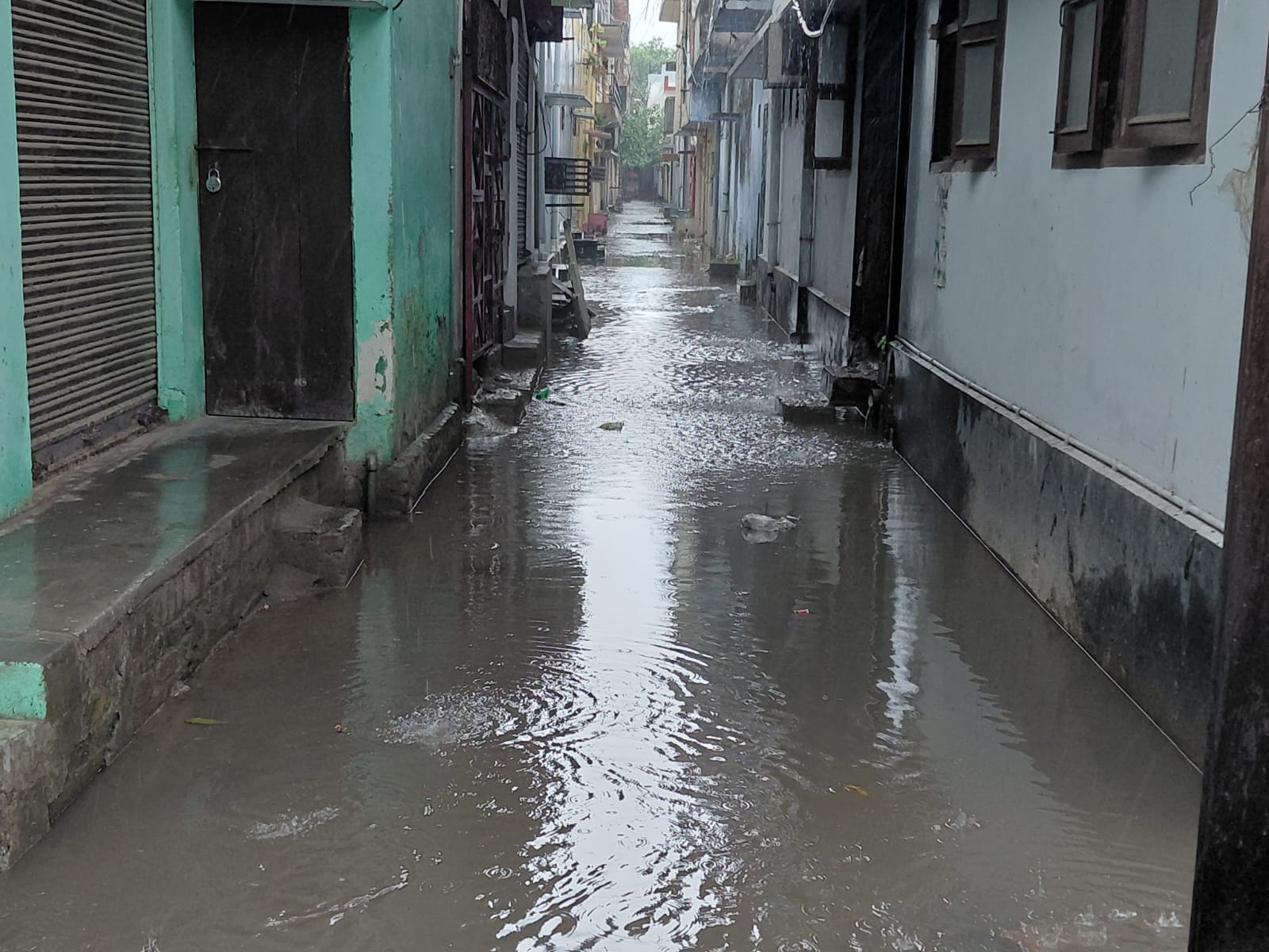 स्टेशन मार्ग पर भरे तालाब जैसे पानी से गुजरते राहगीर। संवाद