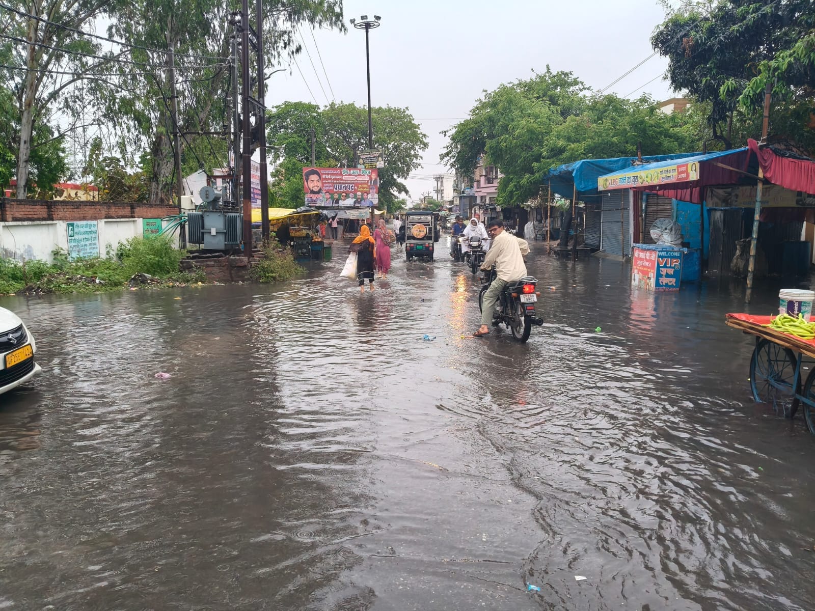 स्टेशन मार्ग पर भरे तालाब जैसे पानी से गुजरते राहगीर। संवाद