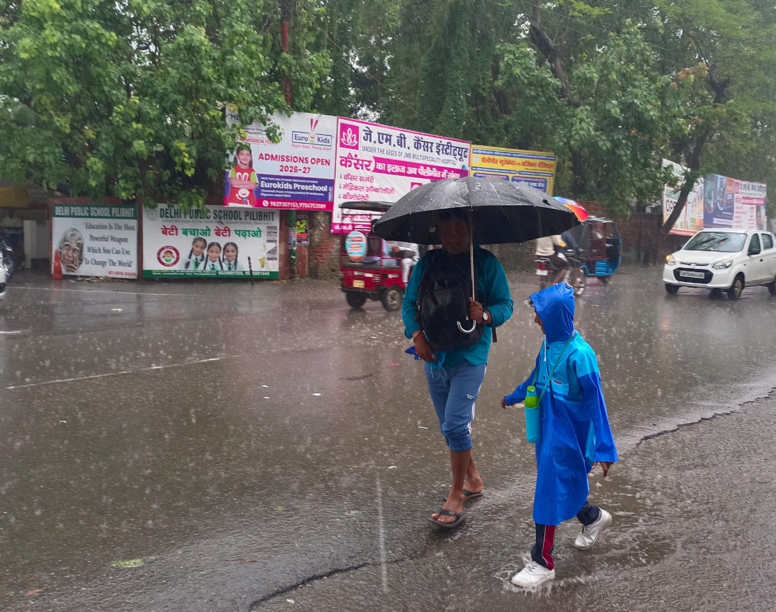 स्टेशन मार्ग पर भरे तालाब जैसे पानी से गुजरते राहगीर। संवाद