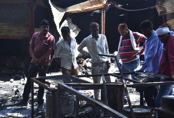 आग बुझने के बाद सामान ढूंढते लोग।