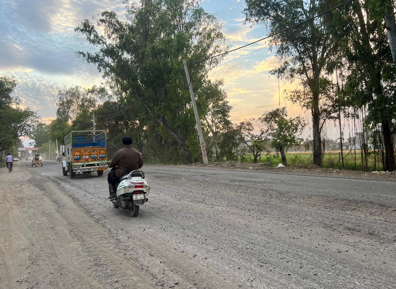 कुरुक्षेत्र। पिपली-लाडवा रोड पर निवारसी मोड़ के निकट उखड़ी सड़क से गुजरते वाहन चालक। संवाद 